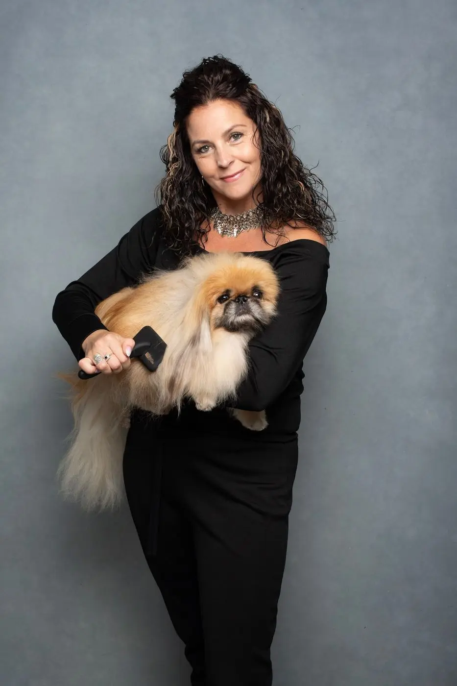 Kelly Davis holding a small, freshly pampered dog at the KD Pet Spa
